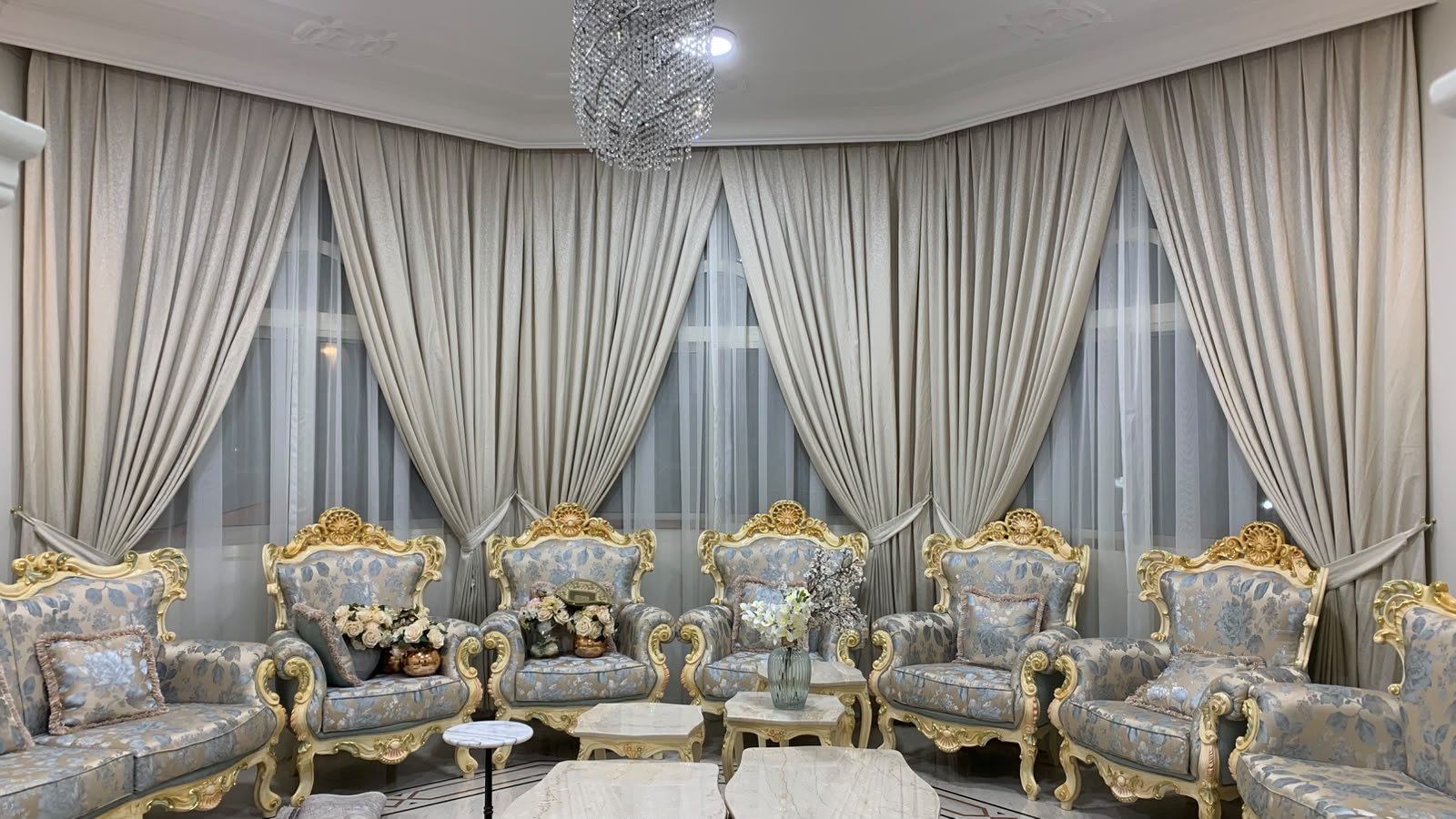 A grey upholstered sofa, wood coffee tables and floor-to-ceiling curtains